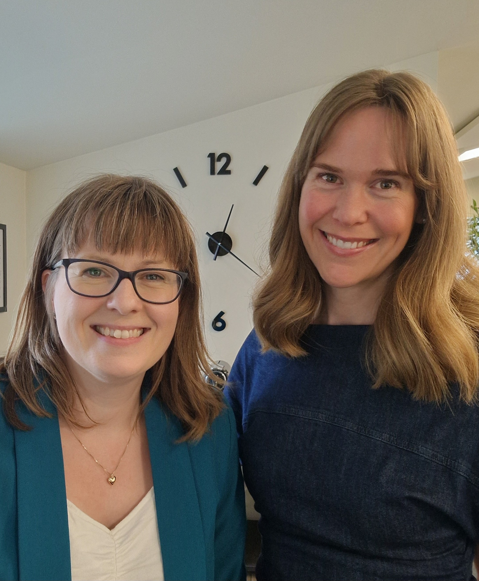 Lisbeth i turkis blazer foran et ur i podcaststudiet